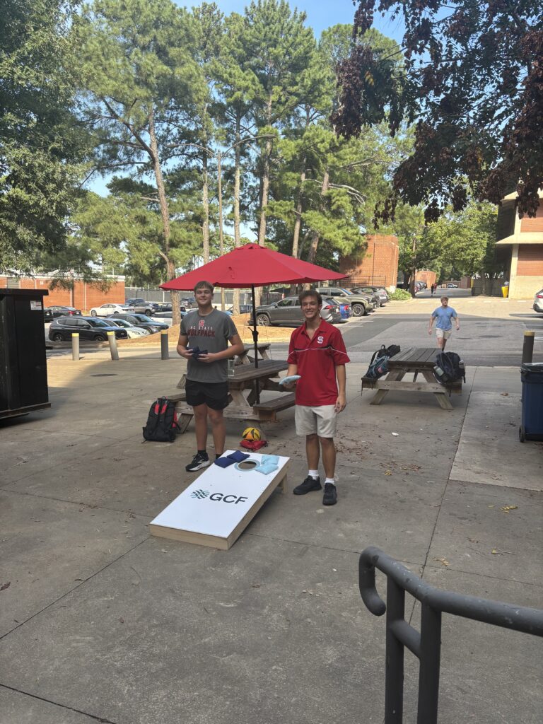 two PSE FYEs play corn hole with the new boards donated by GCF