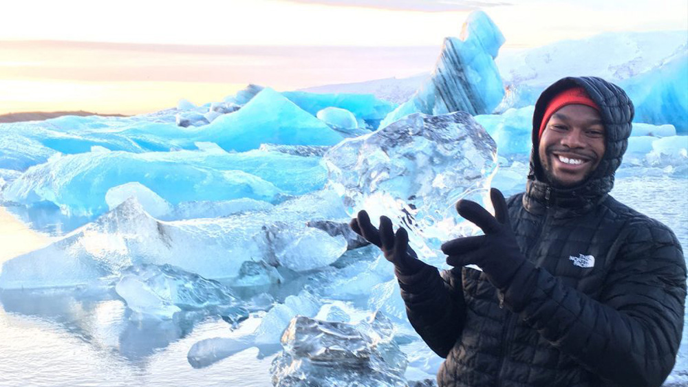 Student smiling with glaciers while holding a block of ice - Environmental Sciences - Forestry and Environmental Resources NC State University