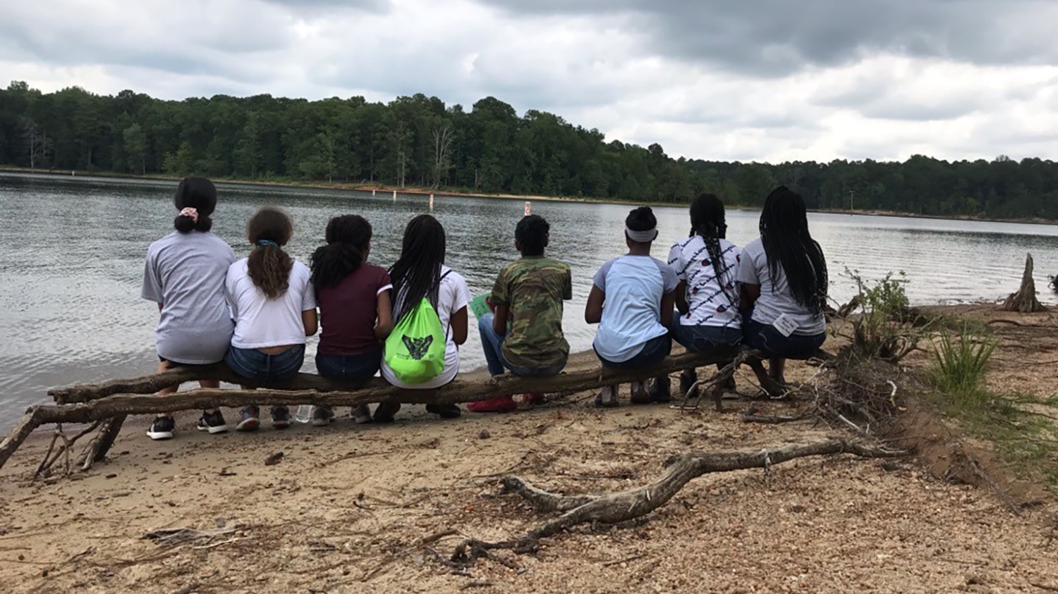 A group of middle school students sit on a log and look out onto a lake - Mentorship is Kay to Inclusion in Ecology - Forestry and Environmental Resources NC State University