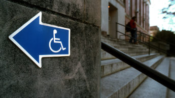a sign points to a wheelchair accessible entrance near a set of stairs