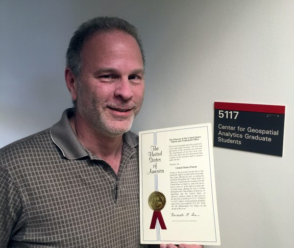 Paul Schrum holding his newly granted patent at the North Carolina State University Center for Geospatial Analytics