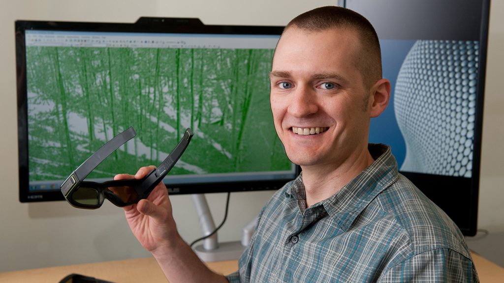 A photo of Zac Arcaro in the visualization lab at the North Carolina State University Center for Geospatial Analytics