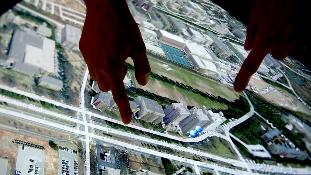 An image of hands on a touch screen at the North Carolina State University Center for Geospatial Analytics