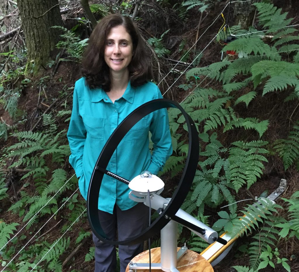 A photo Laura Belica using pyranometers to measure solar radiation in a forest.
