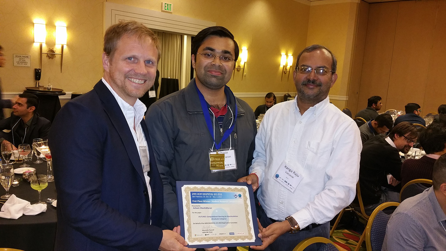 A photo of Ashwin Shashidharan standing with his advisors, Ross Meentemeyer and Raju Vatsavai, and holding an award at the ACM SIGSPATIAL Conference