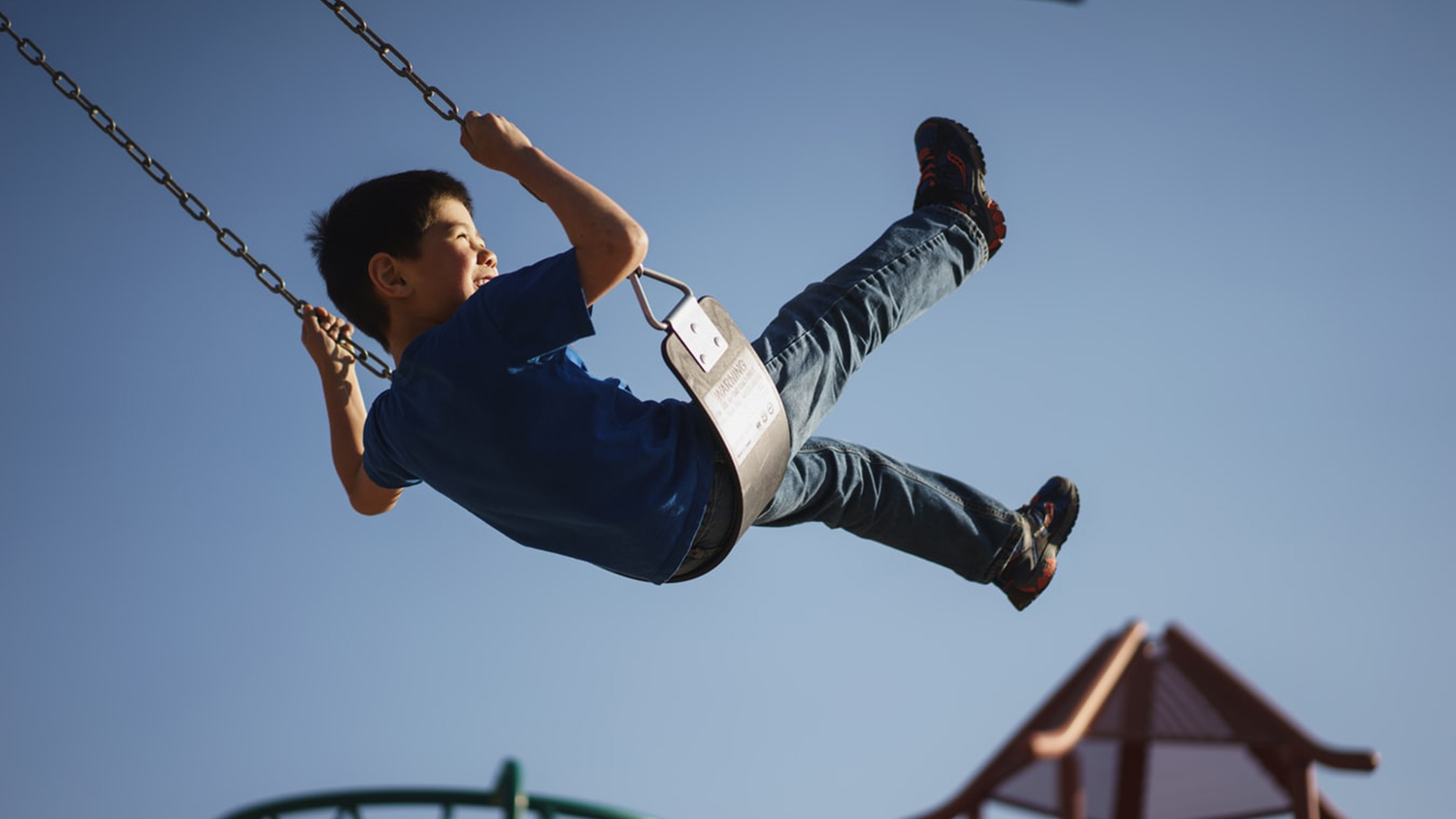 a child enjoys swinging on the swing set of a playground