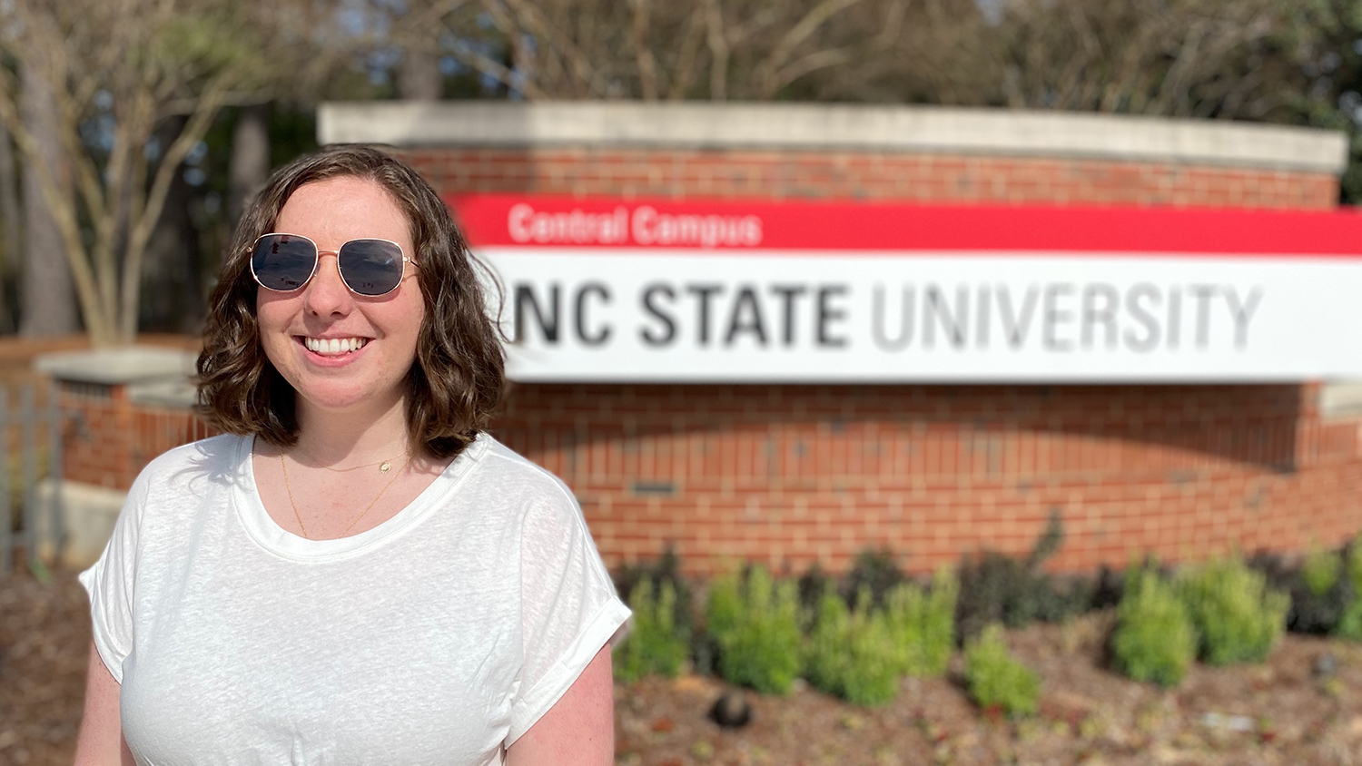 Shannon McAvoy stands in front of an NC State University sign