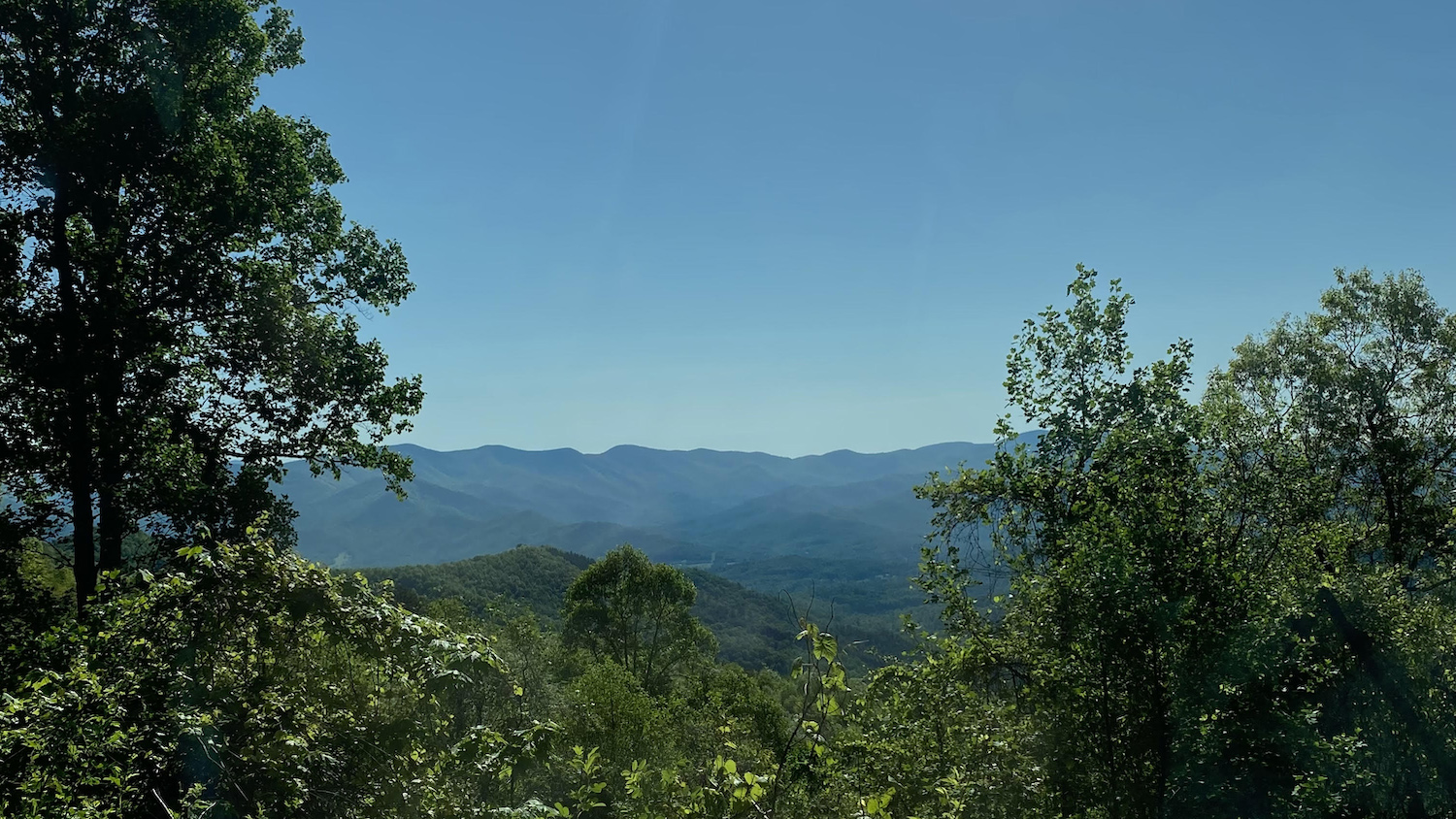 view of mountains against a blue sky with trees in the foreground