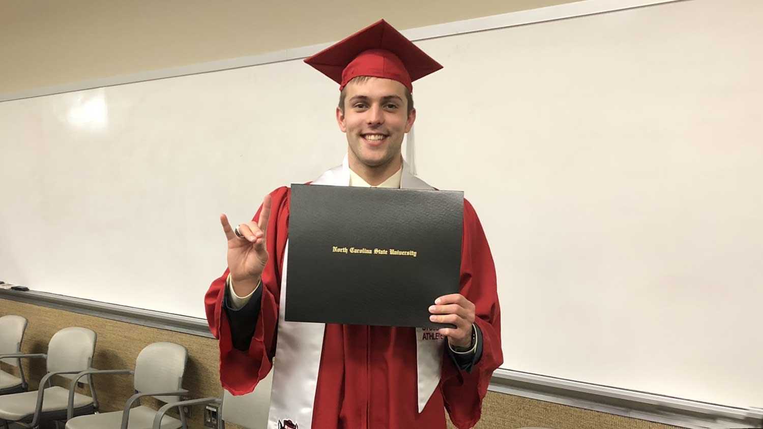 Ryan Held holding diploma after graduation ceremony