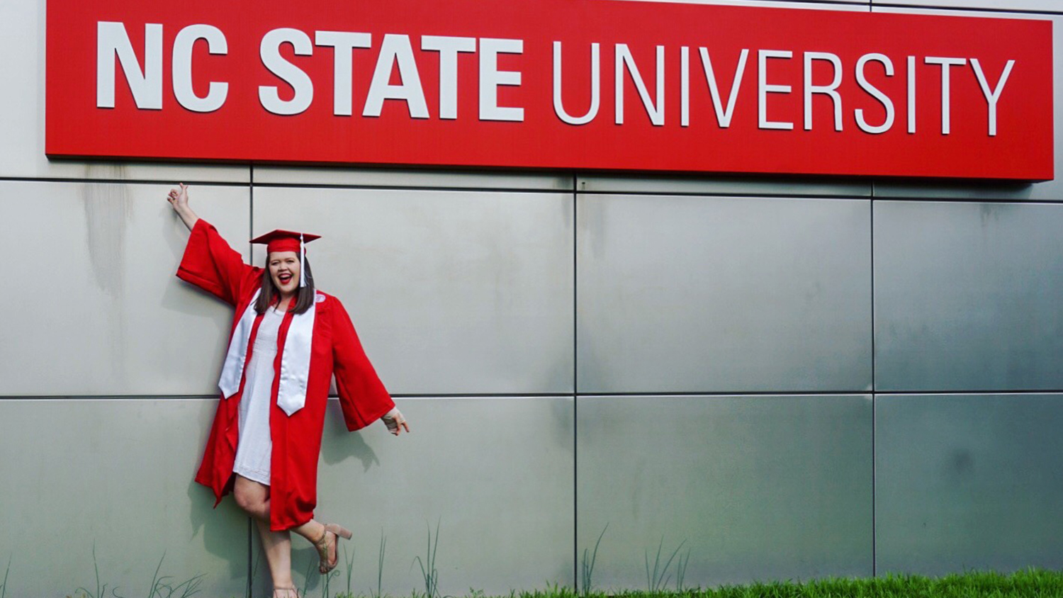 Student in front of NC State sign