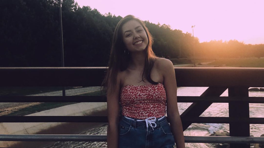 Student poses at sunset on bridge