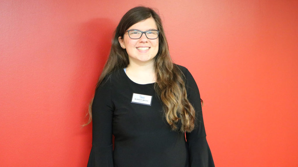 Student poses in front of red wall