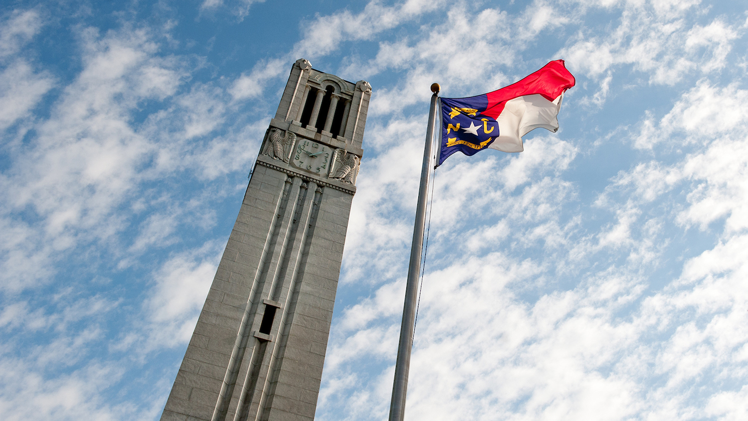 North Carolina flag flies beside by the NC State Belltower