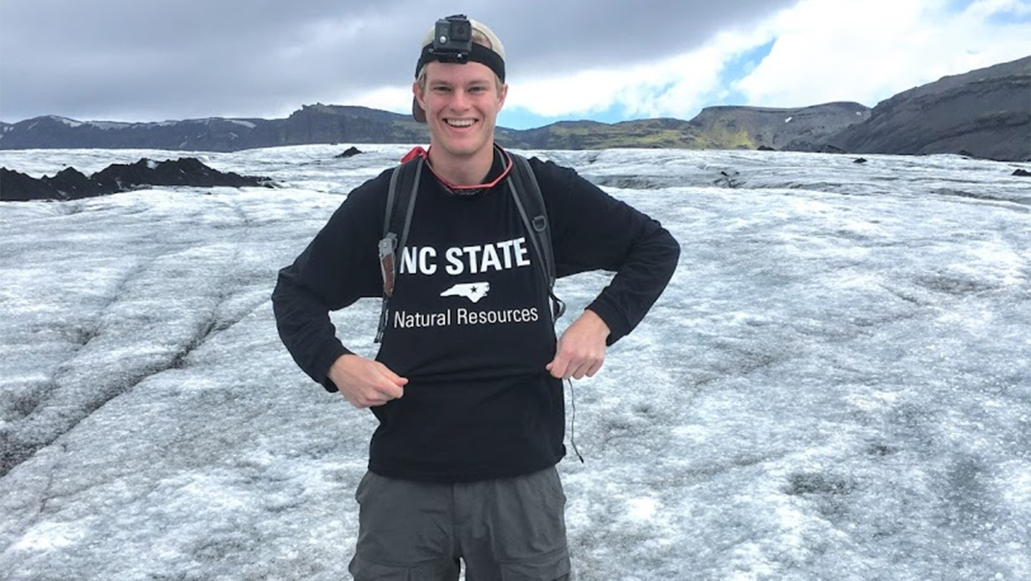 Matthew poses outside with NC State hoodie