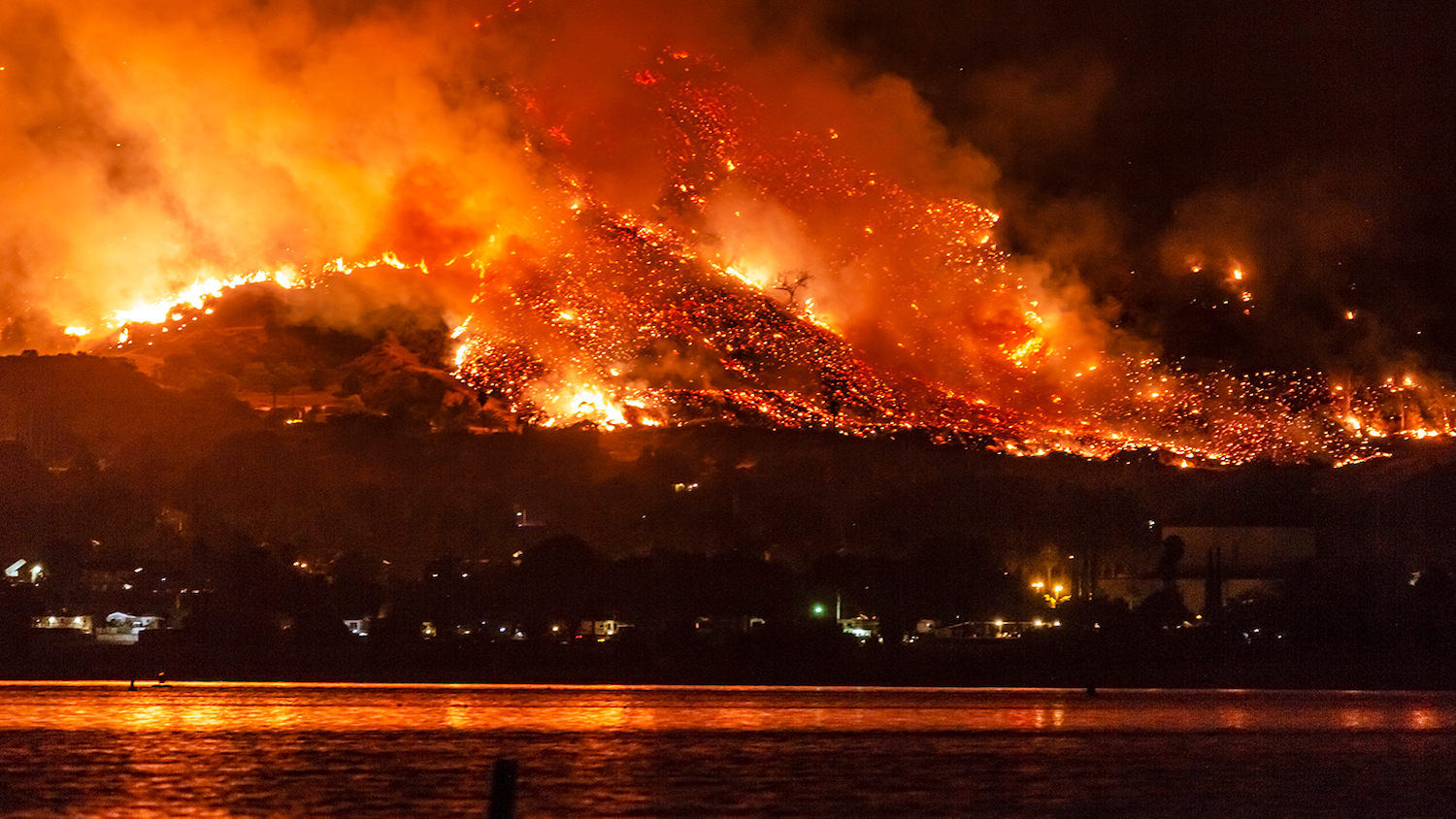 A wildfire burns near a lake in California.