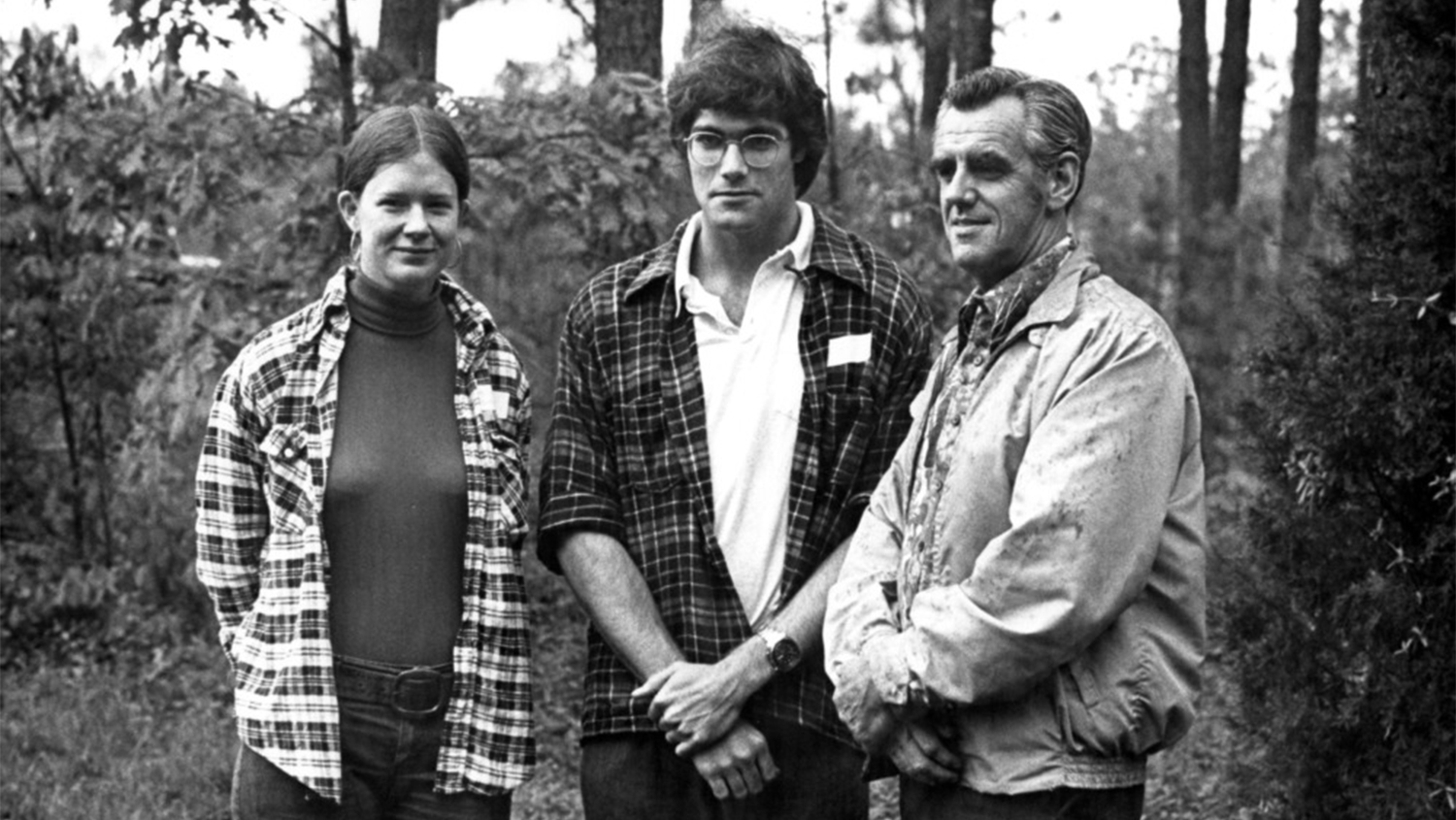 Dean Ellwood poses in woods with two students