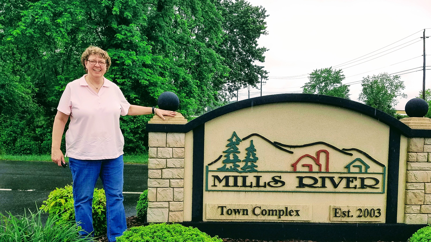 Charlynne stands in front of Town of Mills River sign