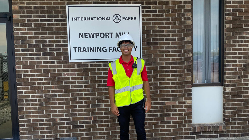 Kelvin Borges stands in front of International Paper sign