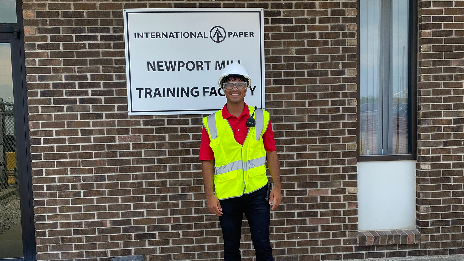 Kelvin Borges stands in front of International Paper sign