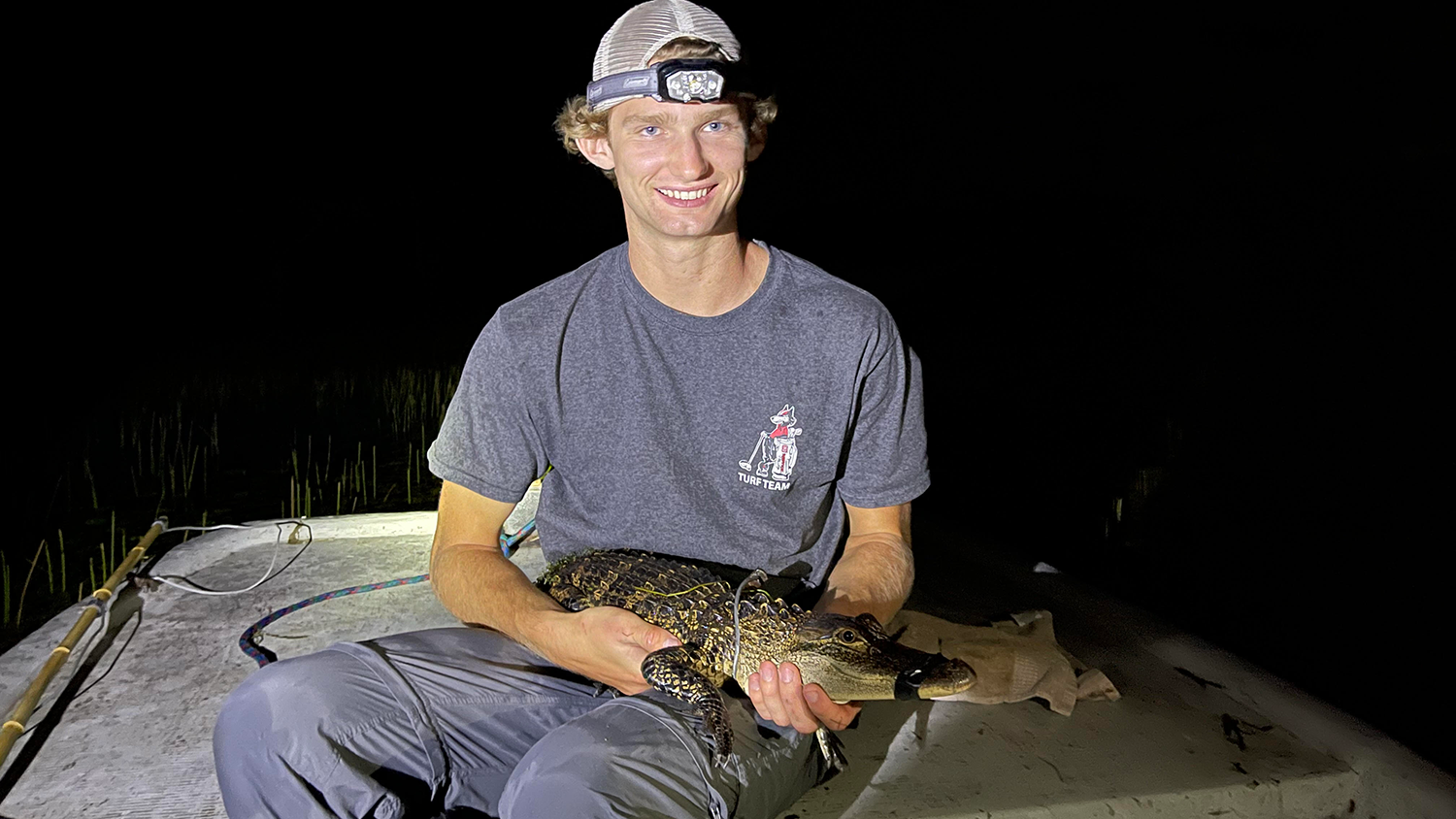Jack Elvin, a senior majoring in fisheries, wildlife and conservation biology, holds a juvenile alligator.