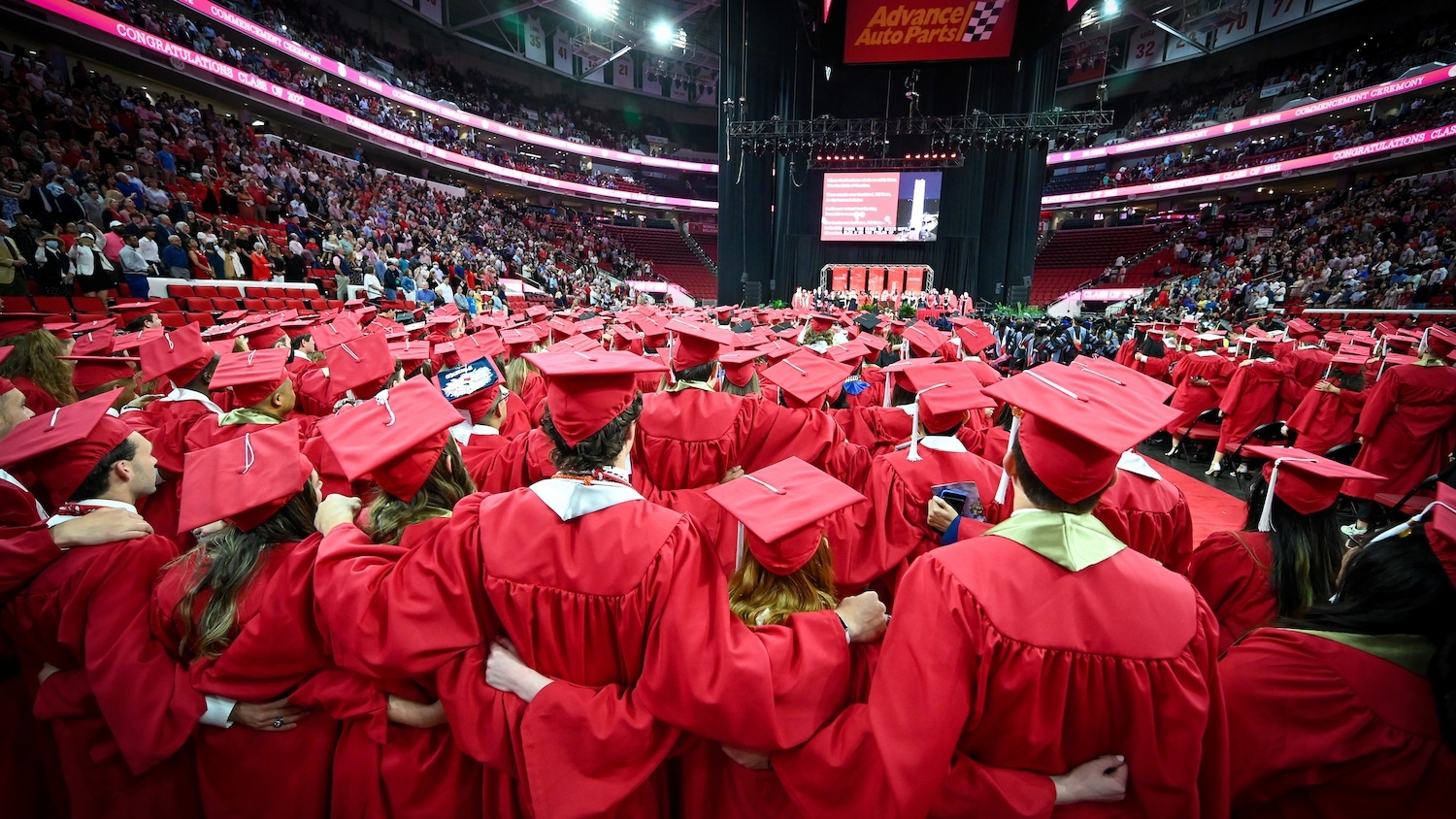 Graduates stand together and embrace each other during the commencement ceremony at PNC Arena.