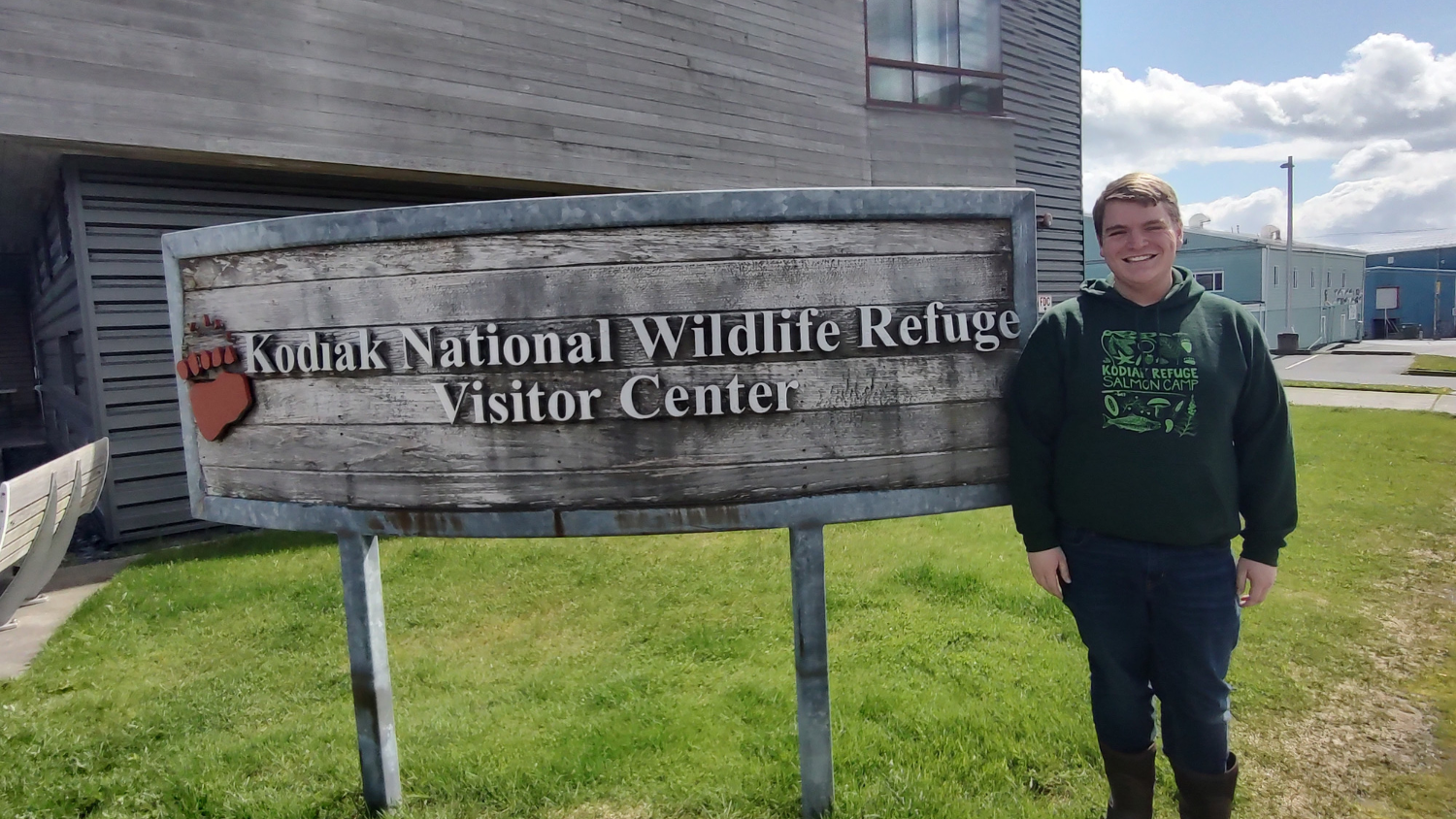 John poses in front of sign - John Mark Polk Educates Kids About Alaska's Habitats - College of Natural Resources at NC State University