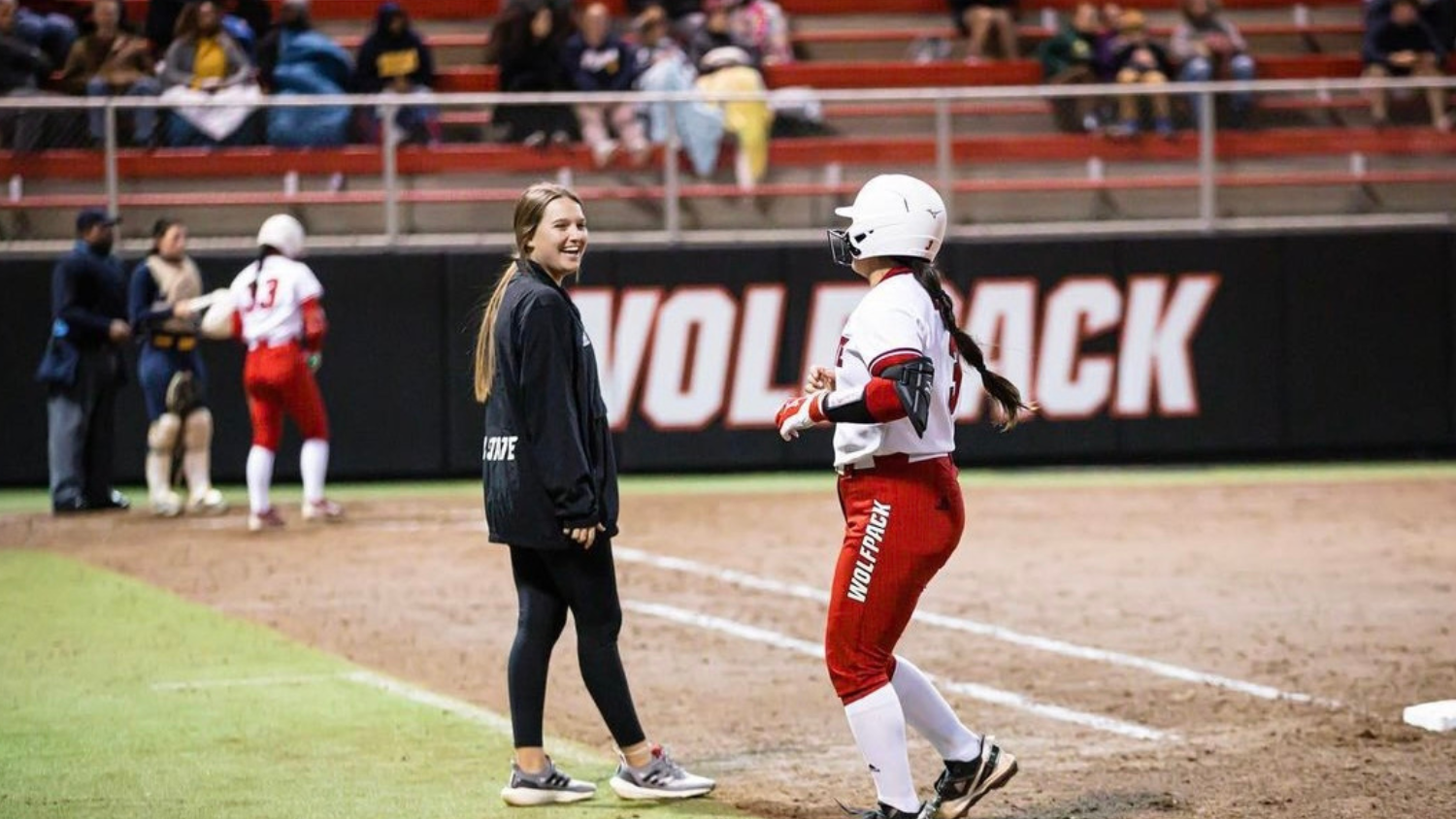 Carson Shaner talks to a softball player on the field.