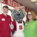A smiling couple poses with Mrs. Wuf