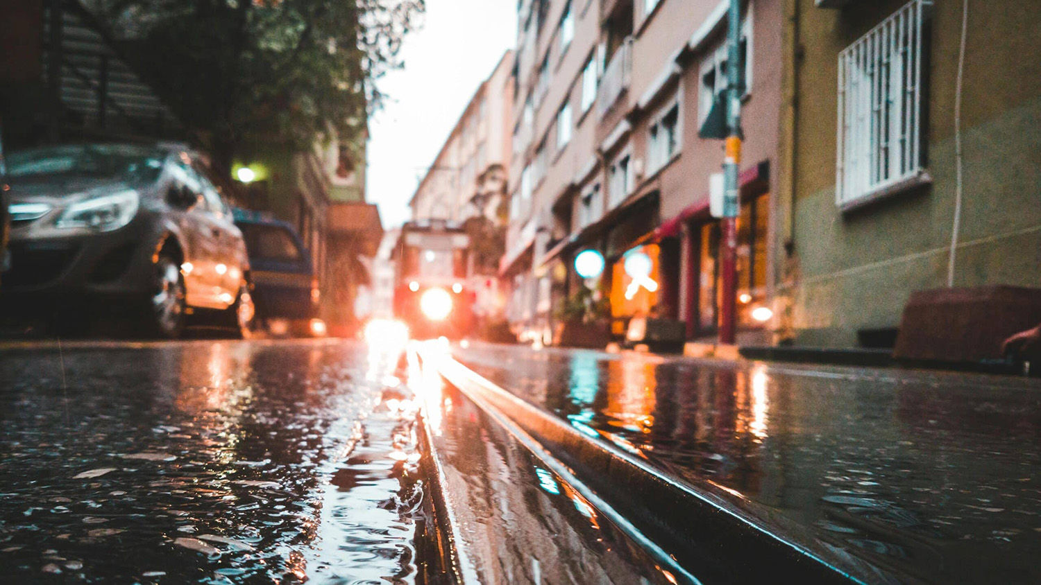 View of flooded street with cars and train.