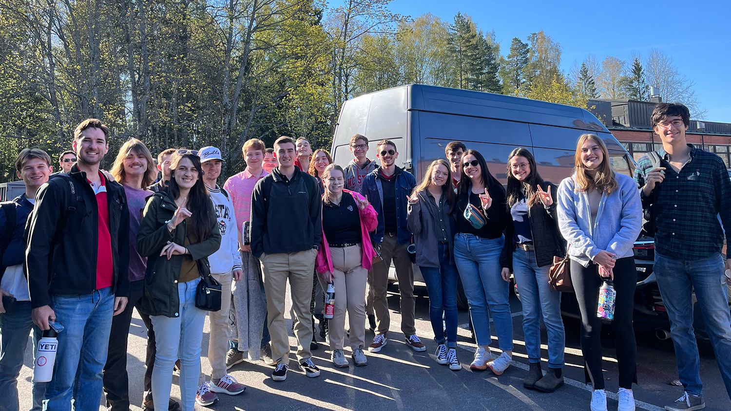 A group of students standing in front of a van.