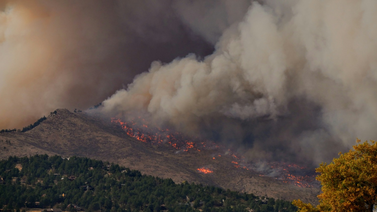 A wildfire emitting smoke from a Colorado mountainside.