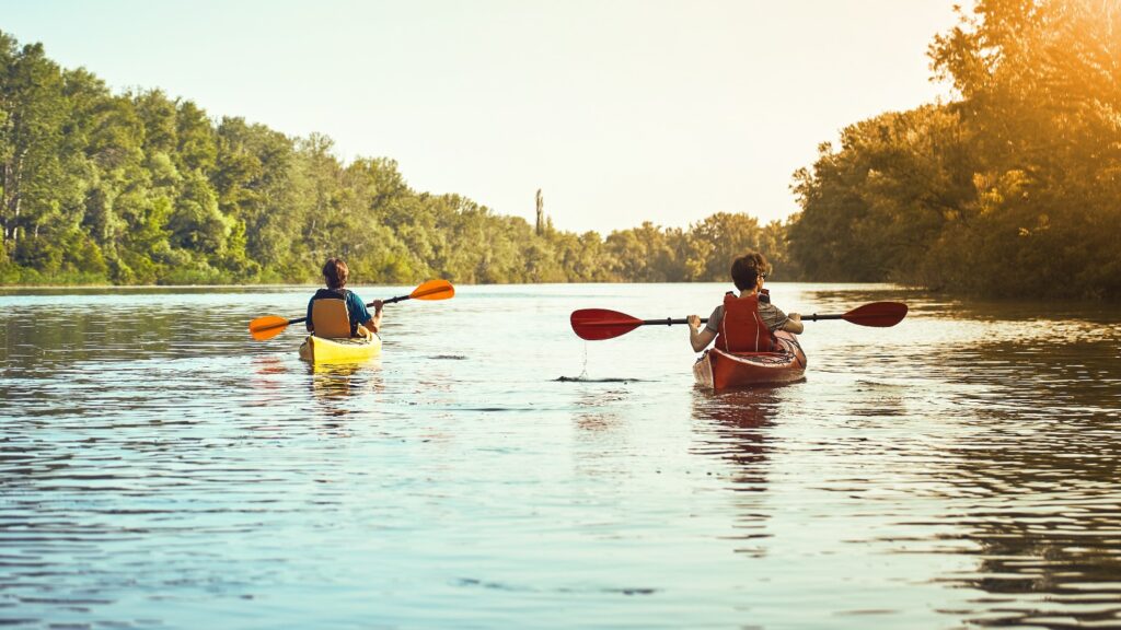 Two people canoeing along a river.