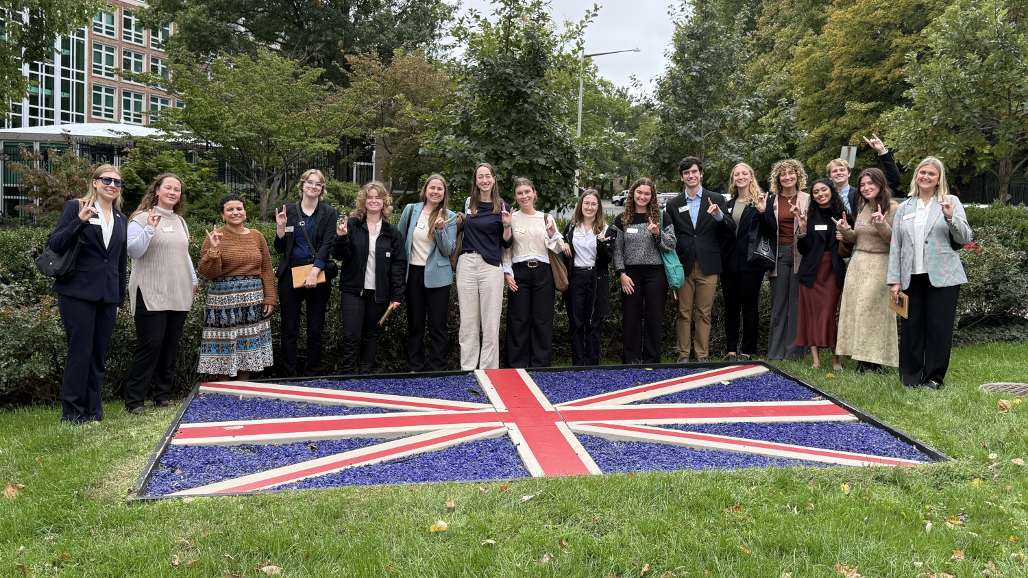 Group picture at the British Embassy, on a lawn with the British flag. - College of Natural Resources at NC State University