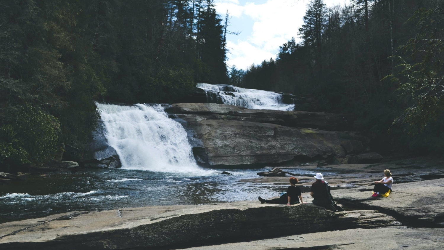 Three people view a waterfall