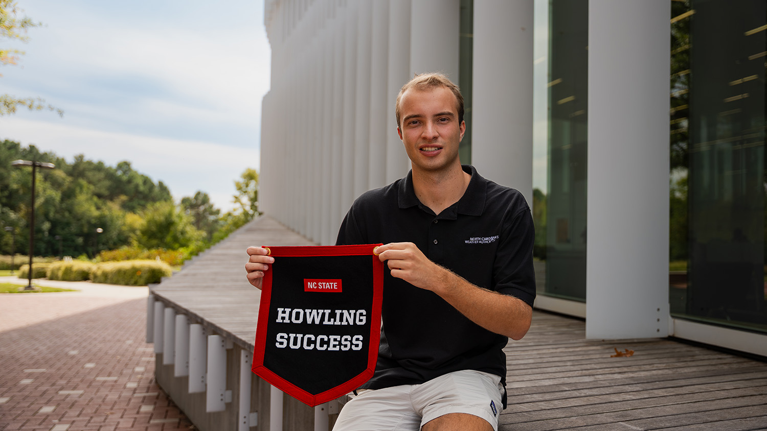 Ethan Clark displays his Howling Success banner outside Hunt Library - College of Natural Resources at NC State University